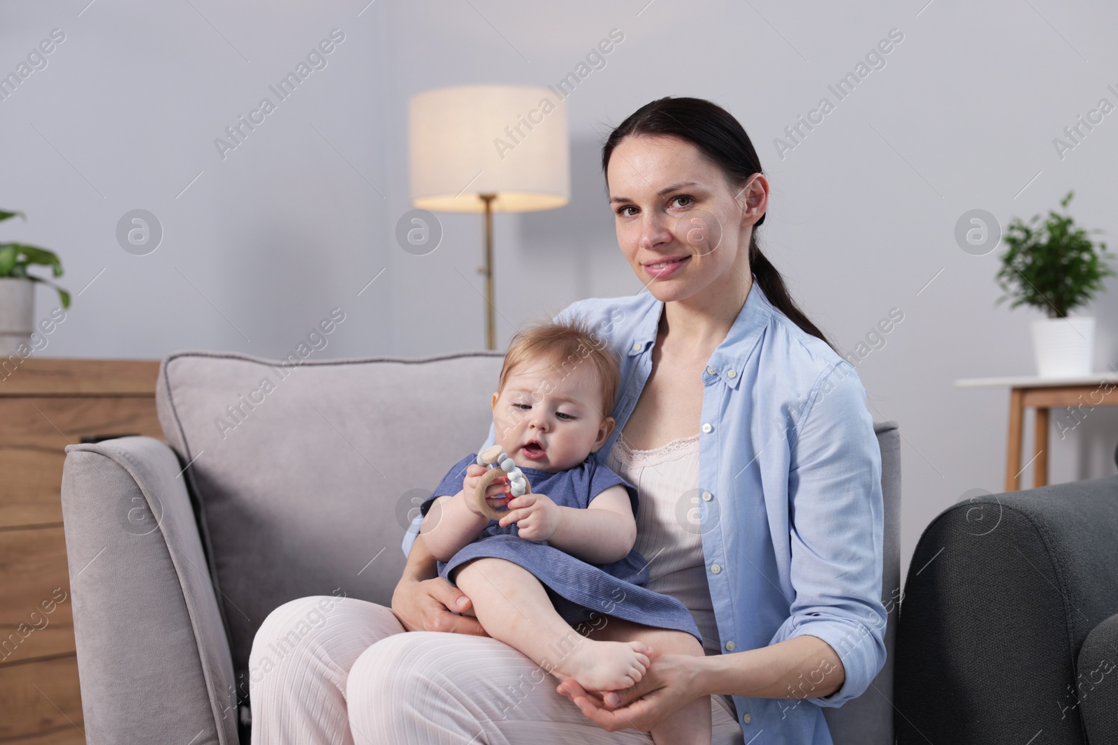 Smiling mother with her little baby on armchair indoors Photo of Smiling mother with her little baby on armchair indoors