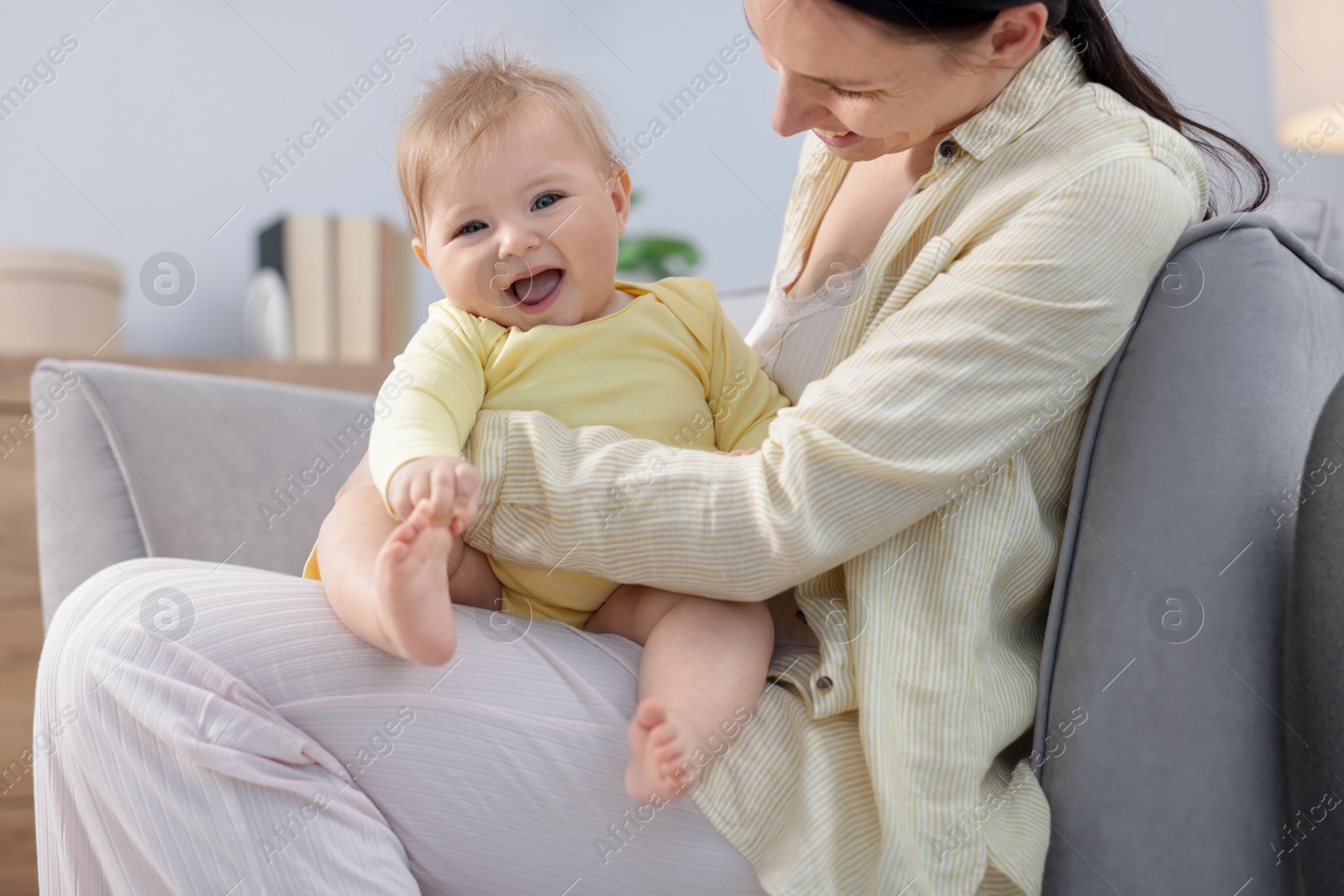 Mother with her little baby on armchair indoors Photo of Mother with her little baby on armchair indoors