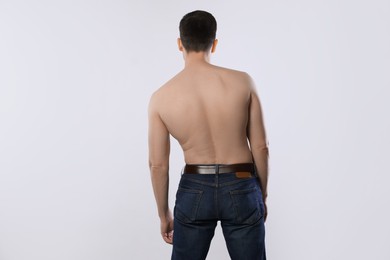 Photo of Man in jeans posing on light grey background, back view