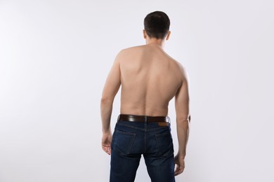 Photo of Man in jeans posing on light grey background, back view