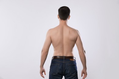 Photo of Man in jeans posing on light grey background, back view