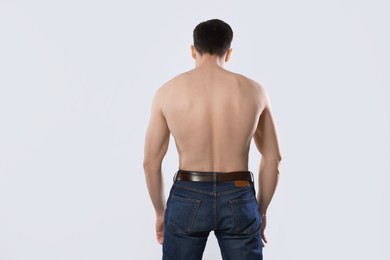 Photo of Man in jeans posing on light grey background, back view