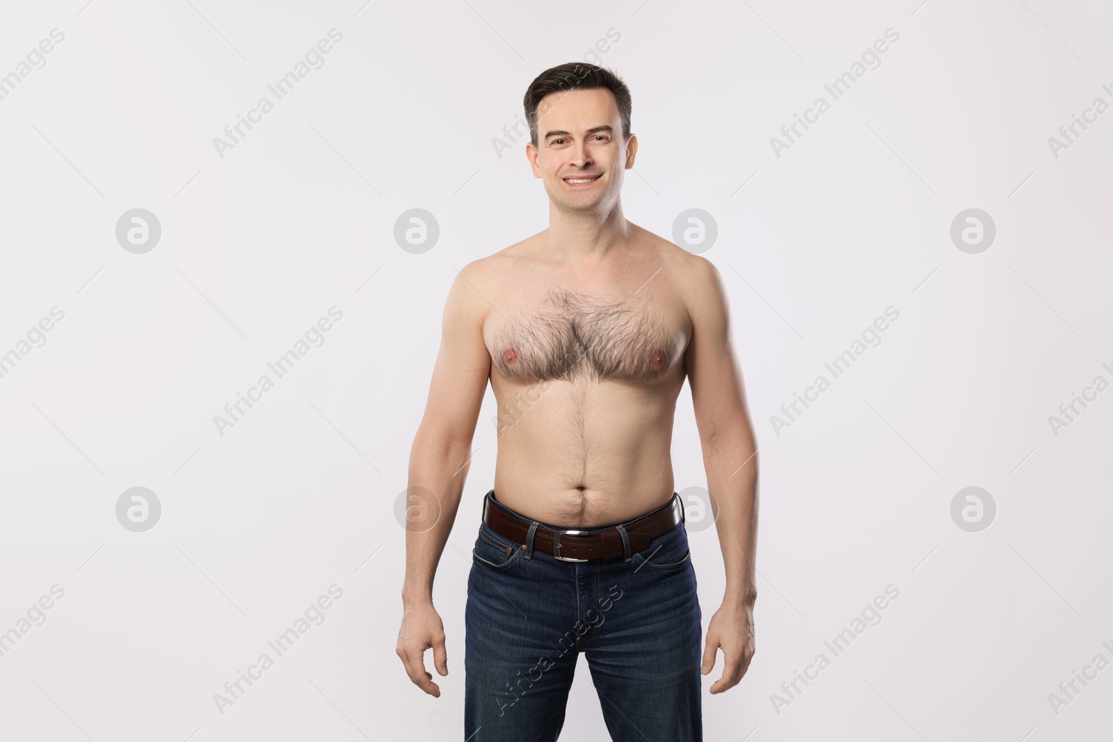Smiling man in jeans posing on light grey background Photo of Smiling man in jeans posing on light grey background