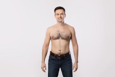 Photo of Smiling man in jeans posing on light grey background