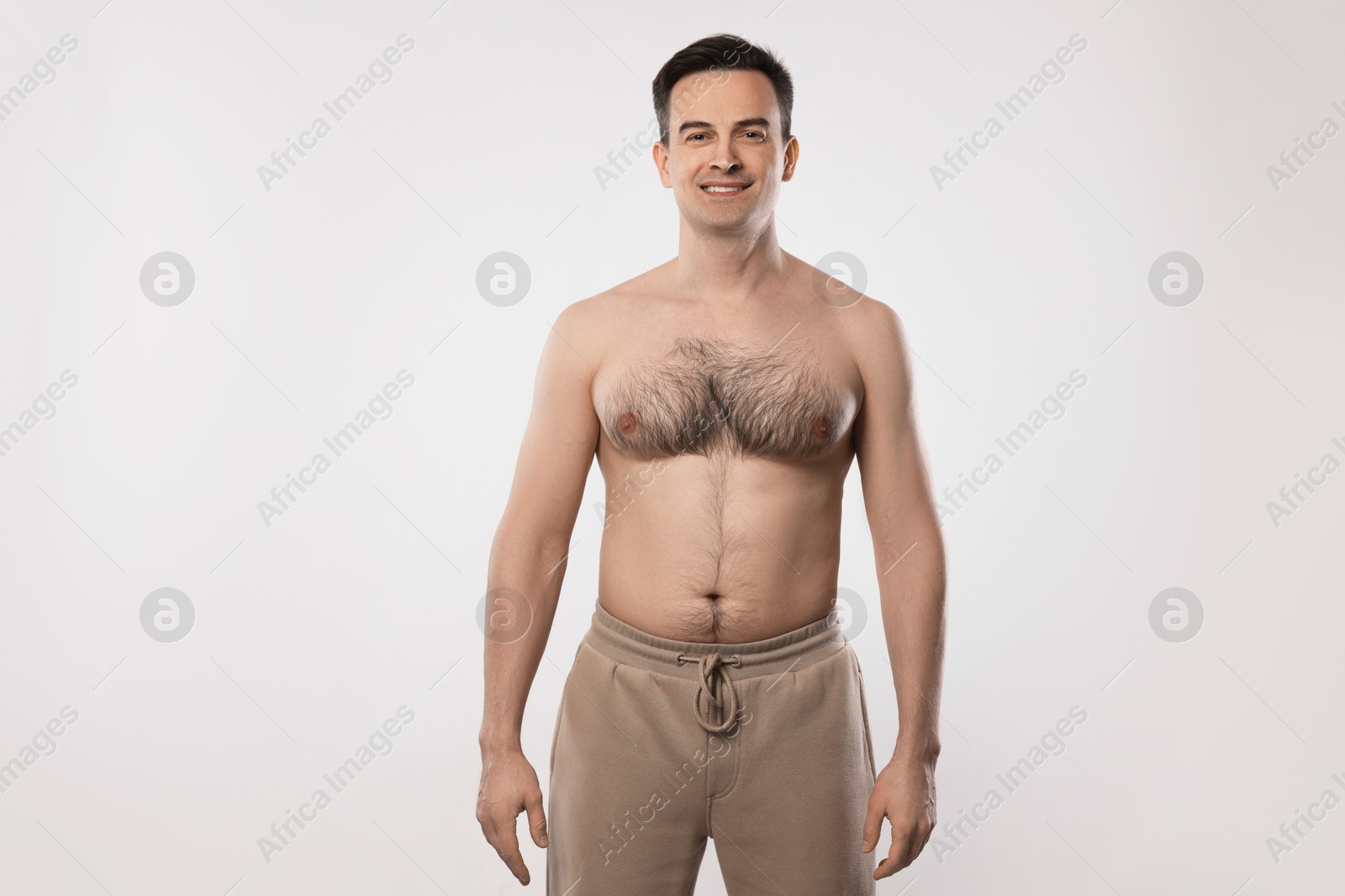 Smiling man in pants posing on light grey background Photo of Smiling man in pants posing on light grey background