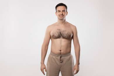 Photo of Smiling man in pants posing on light grey background