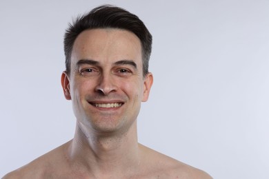 Photo of Portrait of smiling man on light grey background, closeup