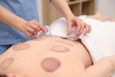 Photo of Therapist giving cupping treatment to patient in spa salon, closeup