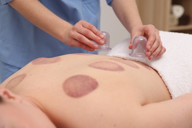 Photo of Therapist giving cupping treatment to patient in spa salon, closeup