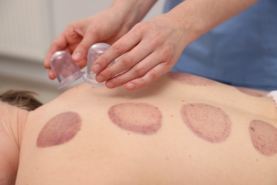 Photo of Therapist giving cupping treatment to patient in spa salon, closeup
