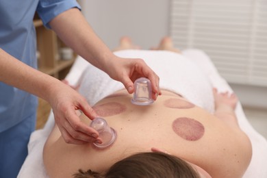 Photo of Therapist giving cupping treatment to patient in spa salon, closeup