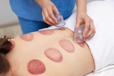 Photo of Therapist giving cupping treatment to patient in spa salon, closeup