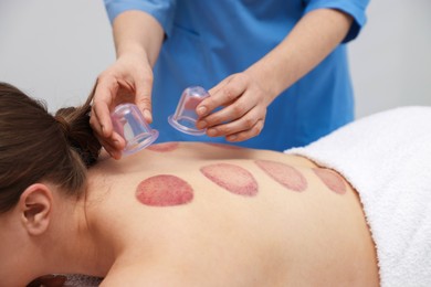 Photo of Therapist giving cupping treatment to patient in spa salon, closeup