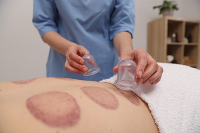 Photo of Therapist giving cupping treatment to patient in spa salon, closeup