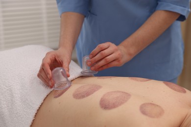 Photo of Therapist giving cupping treatment to patient in spa salon, closeup