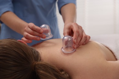 Photo of Therapist giving cupping treatment to patient in spa salon, closeup