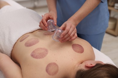 Photo of Therapist giving cupping treatment to patient in spa salon, closeup