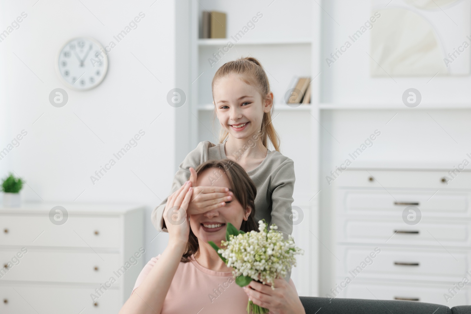 Girl giving her mother beautiful bouquet of lily-of-the-valley flowers at home Photo of Girl giving her mother beautiful bouquet of lily-of-the-valley flowers at home