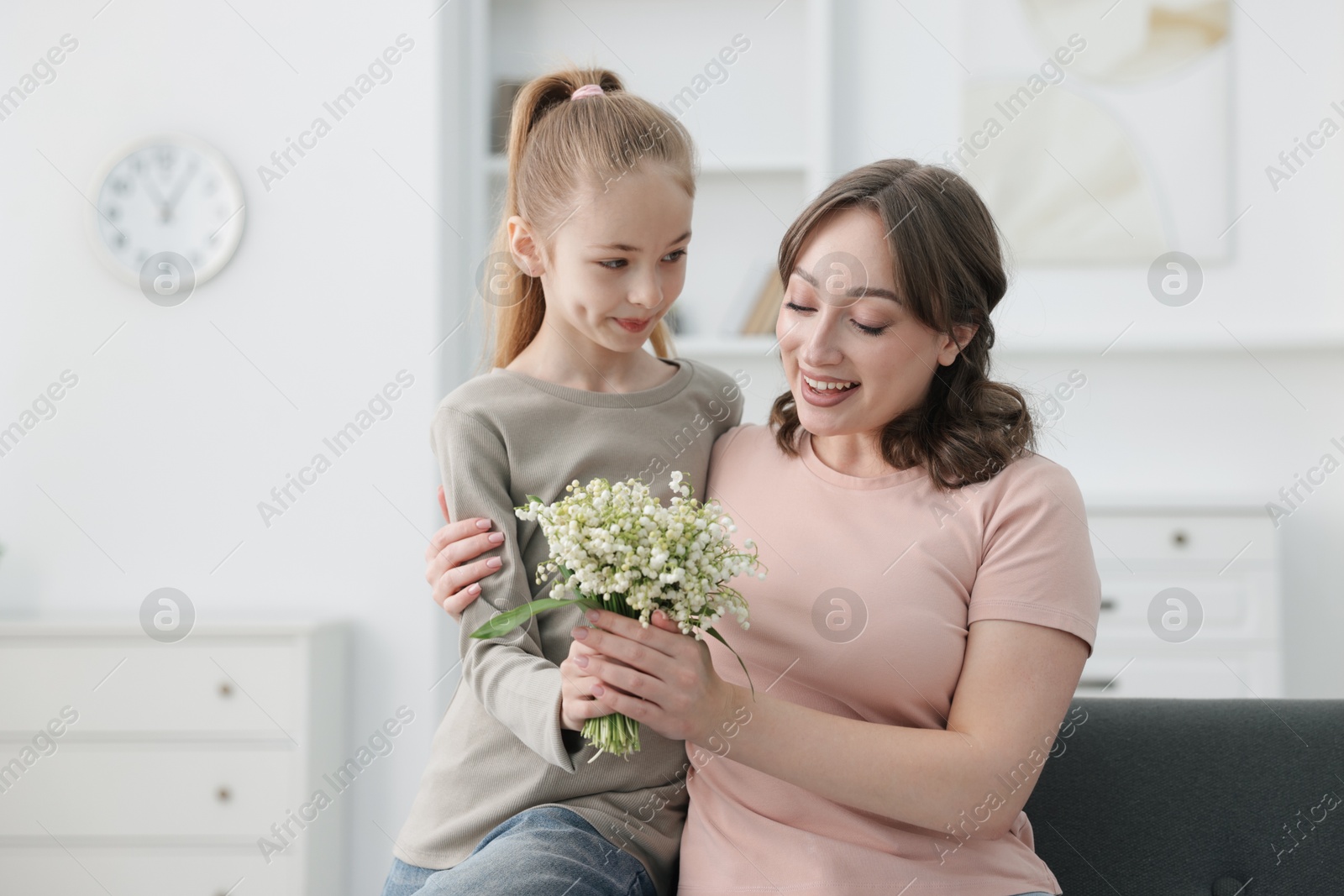 Girl giving her mother beautiful bouquet of lily-of-the-valley flowers at home Photo of Girl giving her mother beautiful bouquet of lily-of-the-valley flowers at home