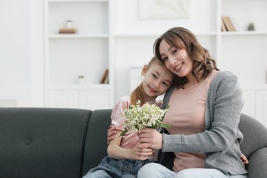 Photo of Girl giving her mother beautiful bouquet of lily-of-the-valley flowers at home. Space for text