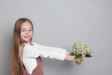 Photo of Girl with bouquet of beautiful lily-of-the-valley flowers on light grey background. Space for text