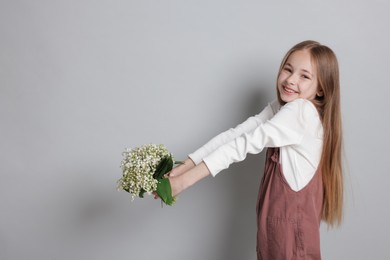 Photo of Girl with bouquet of beautiful lily-of-the-valley flowers on light grey background. Space for text