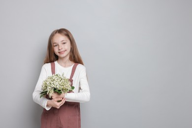 Photo of Girl with bouquet of beautiful lily-of-the-valley flowers on light grey background. Space for text