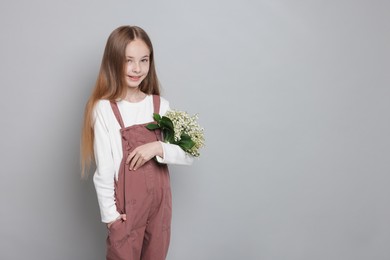 Photo of Girl with bouquet of beautiful lily-of-the-valley flowers on light grey background. Space for text