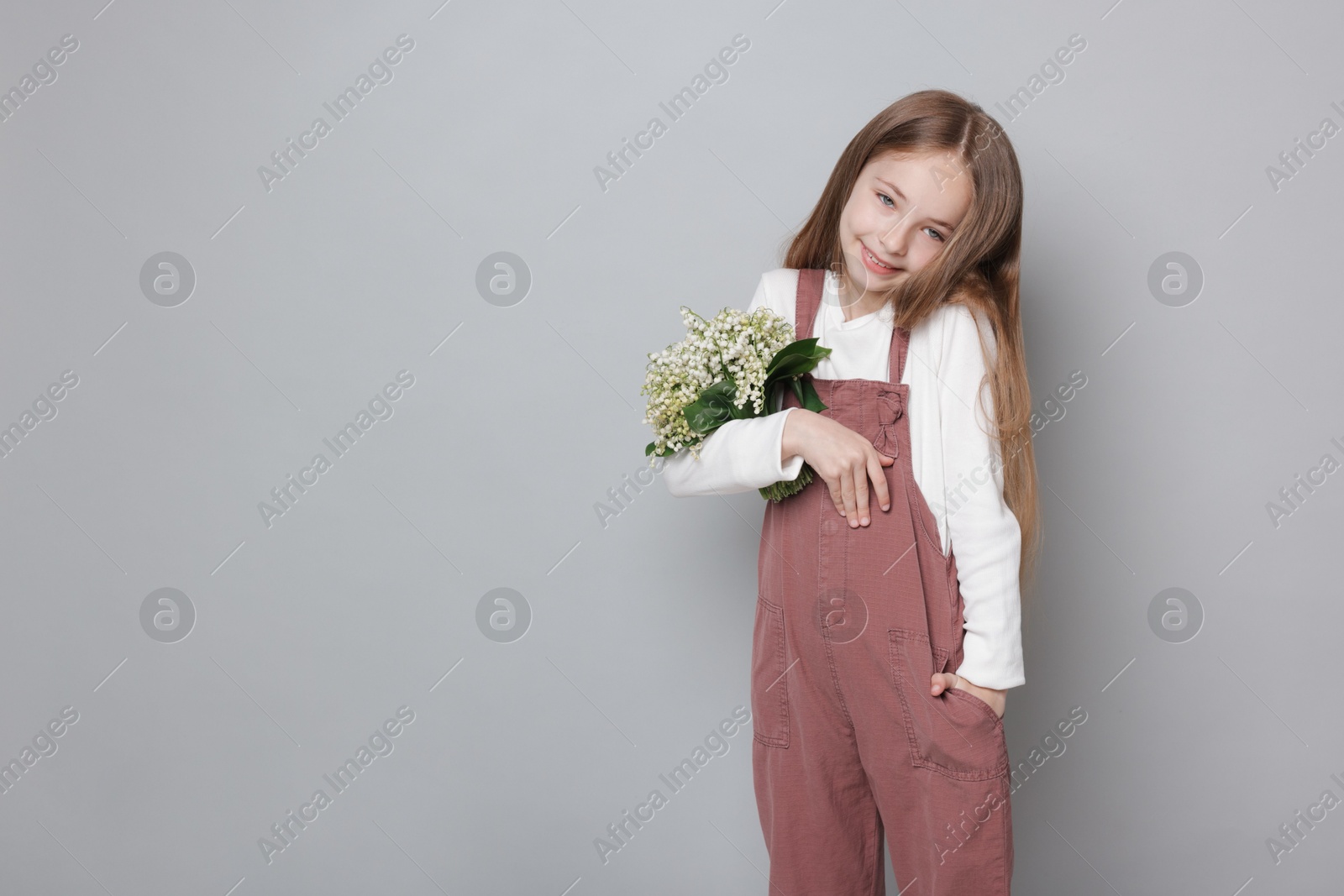 Girl with bouquet of beautiful lily-of-the-valley flowers on light grey background. Space for text Photo of Girl with bouquet of beautiful lily-of-the-valley flowers on light grey background. Space for text