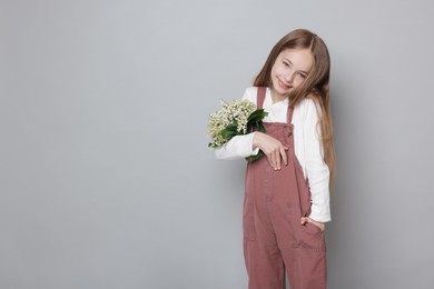 Photo of Girl with bouquet of beautiful lily-of-the-valley flowers on light grey background. Space for text