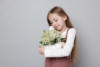 Photo of Girl with bouquet of beautiful lily-of-the-valley flowers on light grey background. Space for text