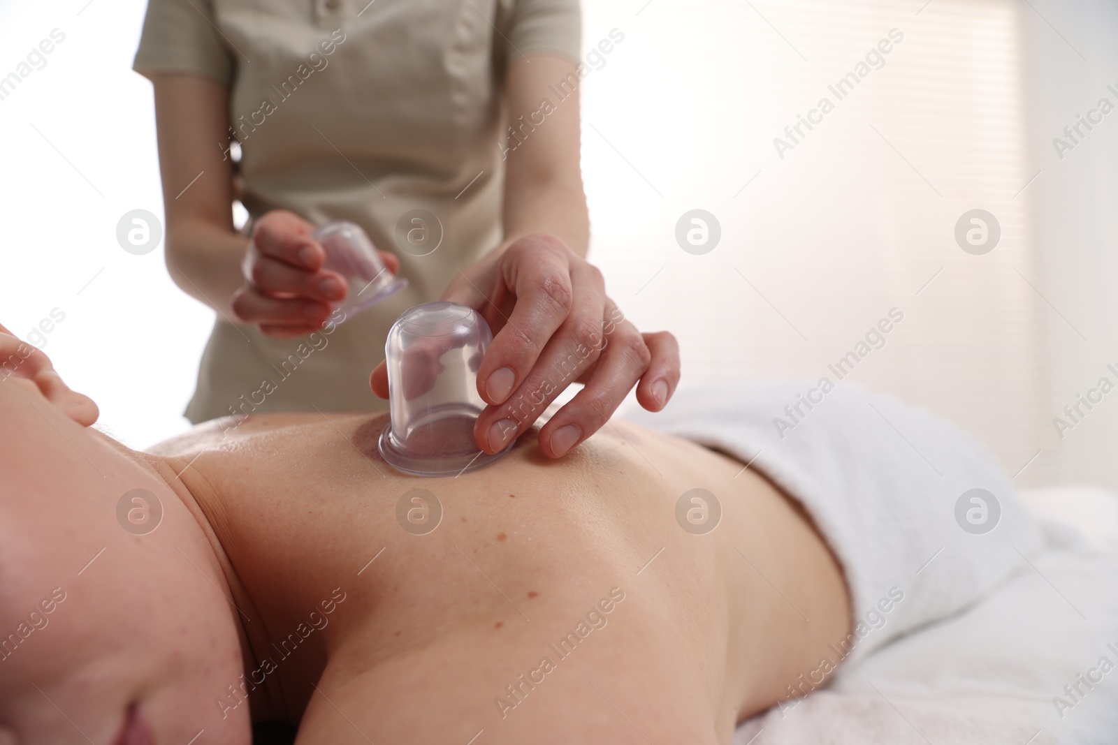 Therapist giving cupping treatment to patient in spa salon, closeup Photo of Therapist giving cupping treatment to patient in spa salon, closeup