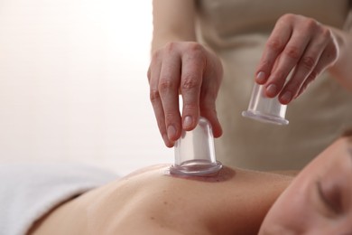 Photo of Therapist giving cupping treatment to patient in spa salon, closeup