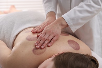 Photo of Cupping therapy. Woman receiving professional massage in spa salon, closeup