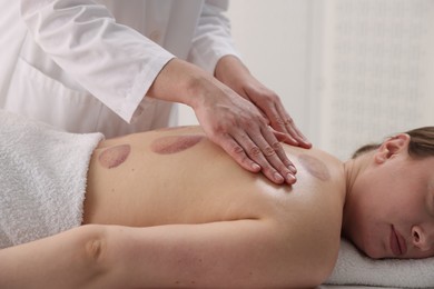 Photo of Cupping therapy. Woman receiving professional massage in spa salon, closeup