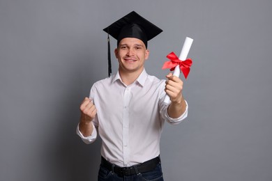 Photo of Happy student with diploma after graduation on grey background