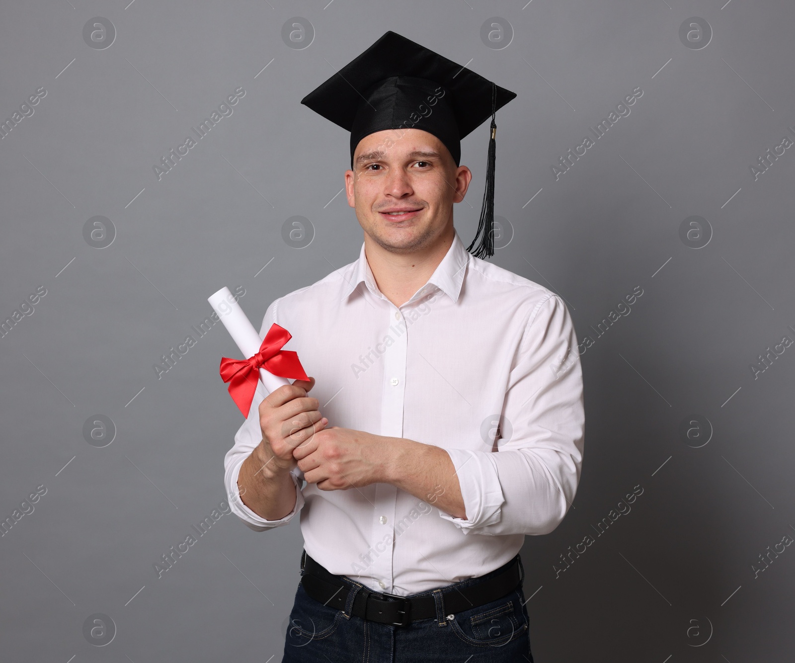 Happy student with diploma after graduation on grey background Photo of Happy student with diploma after graduation on grey background