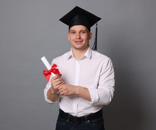Photo of Happy student with diploma after graduation on grey background