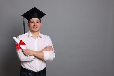Photo of Happy student with diploma after graduation on grey background. Space for text