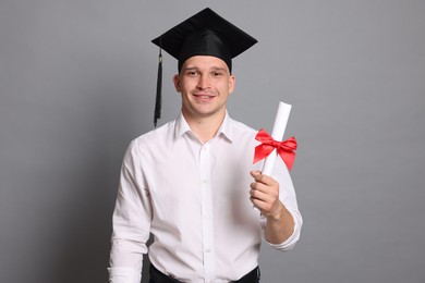 Photo of Happy student with diploma after graduation on grey background