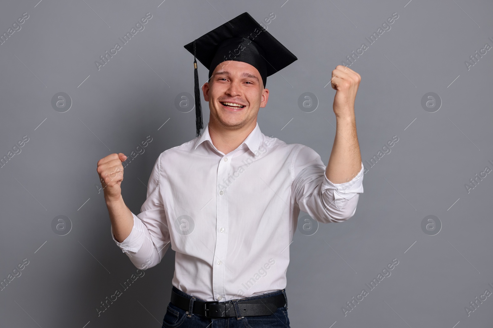 Happy student after graduation on grey background Photo of Happy student after graduation on grey background