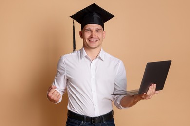 Photo of Happy student with laptop after graduation on beige background