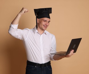 Photo of Happy student with laptop after graduation on beige background