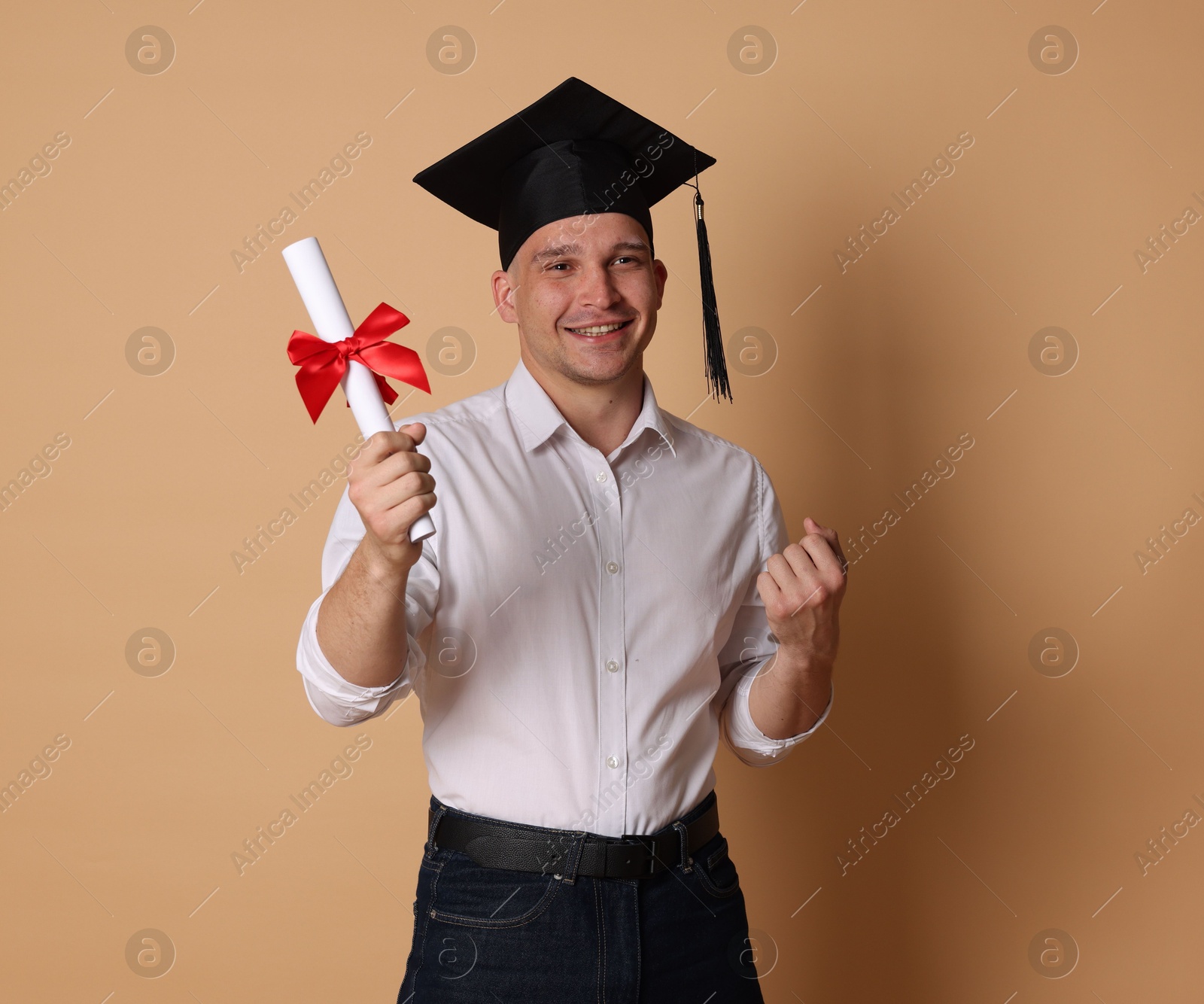 Happy student with diploma after graduation on beige background Photo of Happy student with diploma after graduation on beige background