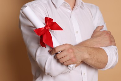 Photo of Student with diploma after graduation on beige background, closeup