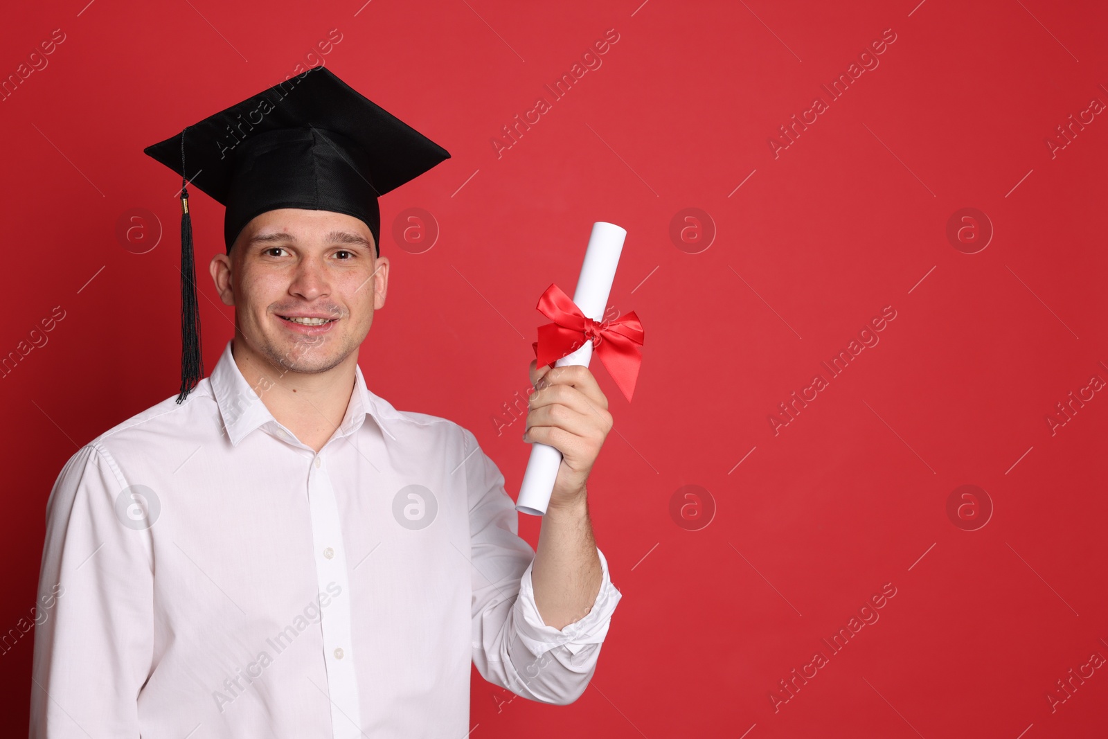 Happy student with diploma after graduation on red background. Space for text Photo of Happy student with diploma after graduation on red background. Space for text