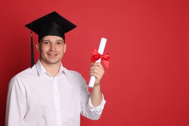 Photo of Happy student with diploma after graduation on red background. Space for text