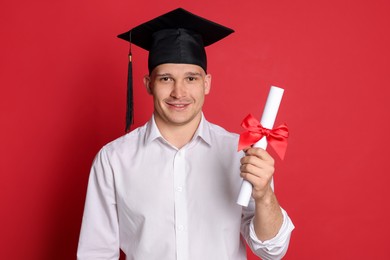 Photo of Happy student with diploma after graduation on red background