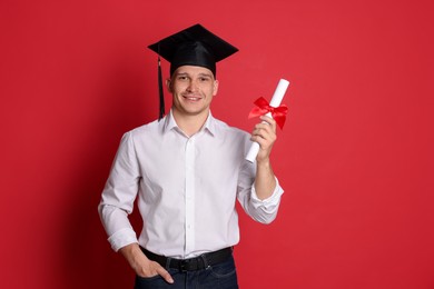 Photo of Happy student with diploma after graduation on red background