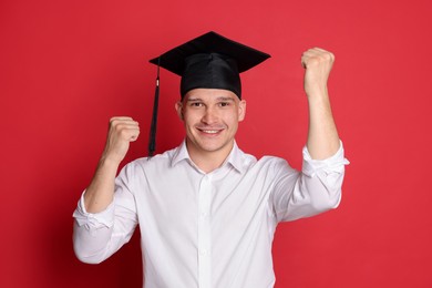 Photo of Happy student after graduation on red background